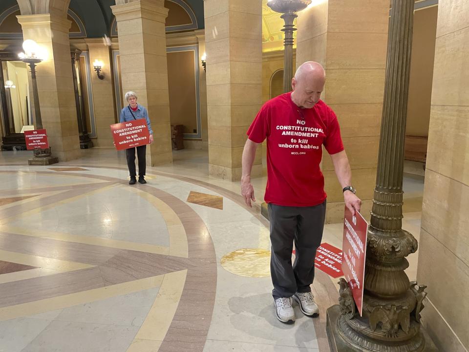 David Mennicke wore a red shirt that said, "No constitutional amendment to kill unborn babies" – in opposition to the Minnesota Equal Rights Amendment – and placed red signs with the same phrase inside the State Capitol building in St. Paul, Minn., on Monday, May 13, 2024. The amendment would guarantee some of the country's most expansive protections of abortion and LGBTQ+ rights if it is approved by both chambers this session and then by voters in two years. (AP Photo/Trisha Ahmed)