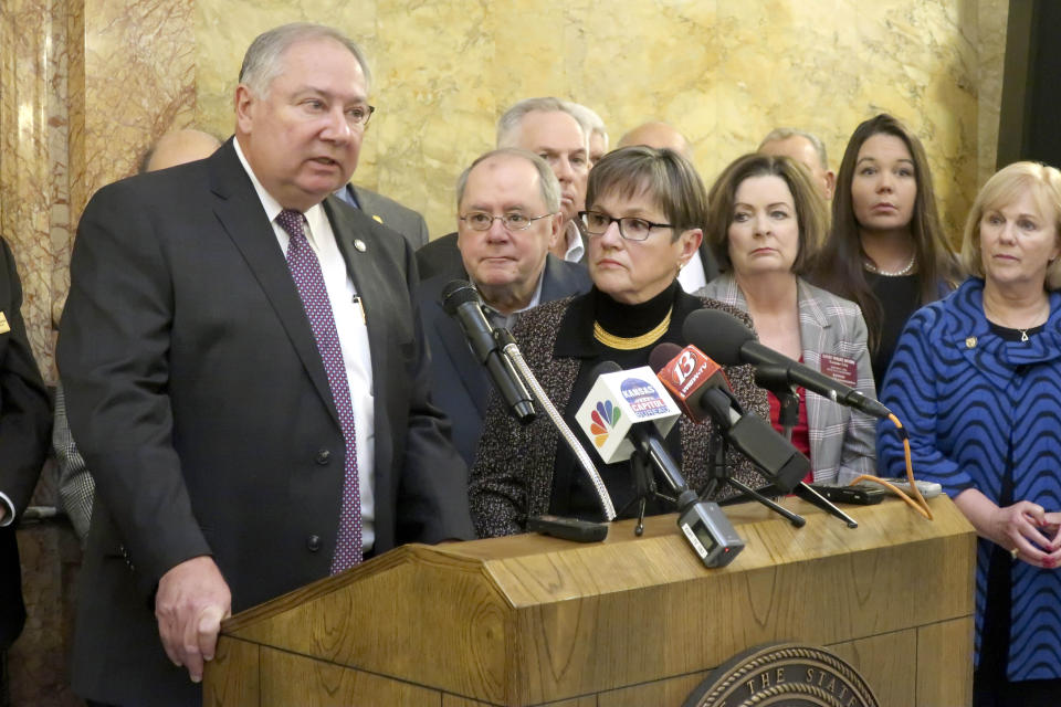 Kansas Senate Majority Leader Jim Denning, R-Overland Park, left, answers reporters' questions about a Medicaid expansion plan as Gov. Laura Kelly, center, and other advocates watch, Thursday, Jan. 9, 2020, at the Statehouse in Topeka, Kansas. (AP Photo/John Hanna)