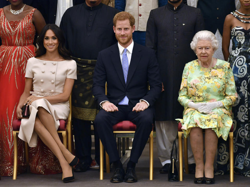 FILE - In this Tuesday, June 26, 2018 file photo, Britain&#39;s Queen Elizabeth, Prince Harry and Meghan, Duchess of Sussex pose for a group photo at the Queen&#39;s Young Leaders Awards Ceremony at Buckingham Palace in London. As part of a surprise announcement distancing themselves from the British royal family, Prince Harry and his wife Meghan declared they will “work to become financially independent” _ a move that has not been clearly spelled out and could be fraught with obstacles.(John Stillwell/Pool Photo via AP, File)