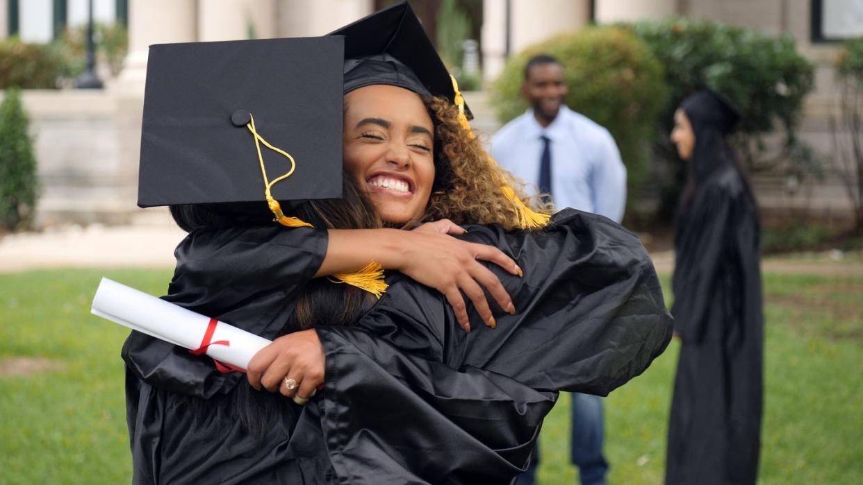 graduate hugs friend post ceremony