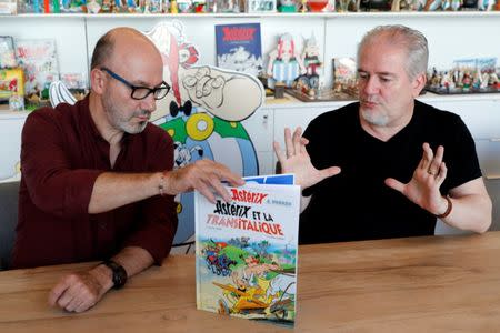 Author Jean-Yves Ferri (L) and illustrator Didier Conrad (R) hold a copy of their new comic album "Asterix et la Transitalique" (Asterix and the Chariot Race) during an interview in Vanves near Paris, France, October 17, 2017, the latest in the series created by illustrator Albert Uderzo and writer Rene Goscinny in 1959. Picture taken October 17, 2017. REUTERS/Philippe Wojazer