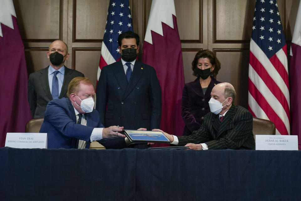 Stan Deal, President and CEO Boeing Commercial Airplanes, left, and Qatar Airways' Chief Executive Akbar al-Baker, right, sign an agreement for the purchase of thirty-four 777-8 Freighter planes with purchase rights for an additional sixteen, in the Eisenhower Executive Office Building on the White House Campus in Washington, Monday, Jan. 31, 2022. Standing behind from left, David Calhoun, CEO, The Boeing Company, Qatar's Emir Sheikh Tamim bin Hamad Al Thani and Secretary of Commerce Gina Raimondo. They also signed a letter of intent for an additional purchase from Qatar Airways of twenty-five 737-10s , worth $6.7 billion. (AP Photo/Carolyn Kaster)