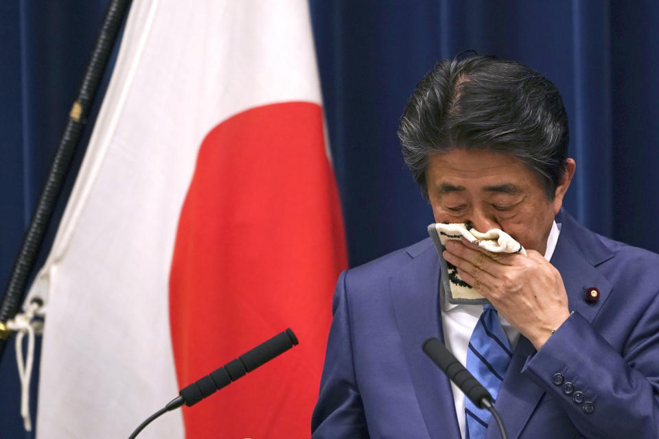 Japanese Prime Minister Shinzo Abe wipes his face as he answers a question during his press conference about the coronavirus situation in Japan, at the Prime Minister's office in Tokyo Saturday, March 14, 2020. (AP Photo/Eugene Hoshiko)