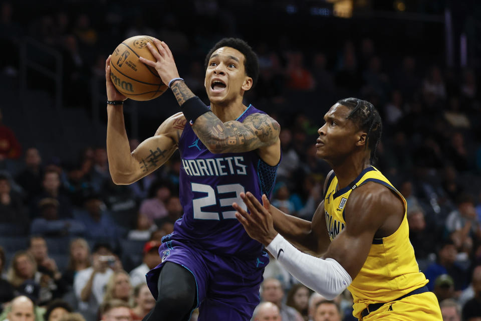 Charlotte Hornets guard Tre Mann (23) drives to the basket against Indiana Pacers guard Bennedict Mathurin, right, during the first half of an NBA basketball game in Charlotte, N.C., Monday, Feb. 12, 2024. (AP Photo/Nell Redmond)