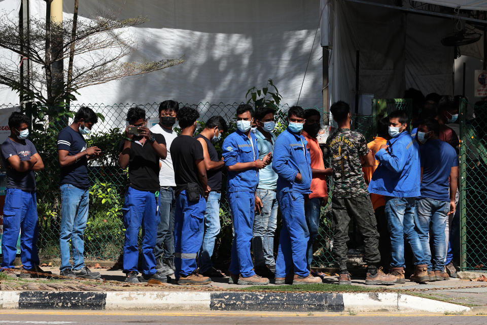 Migrant workers wait in queue to enter a Regional Screening Centre to undergo Rostered Routine Testing (RRT) swab on October 9, 2021 in Singapore. RRT is a surveillance training program for targetted groups who are vulnerable and have higher risk of exposure to COVID-19 which involves recurrent swab testing every 14 days. (Photo by Suhaimi Abdullah/NurPhoto via Getty Images)