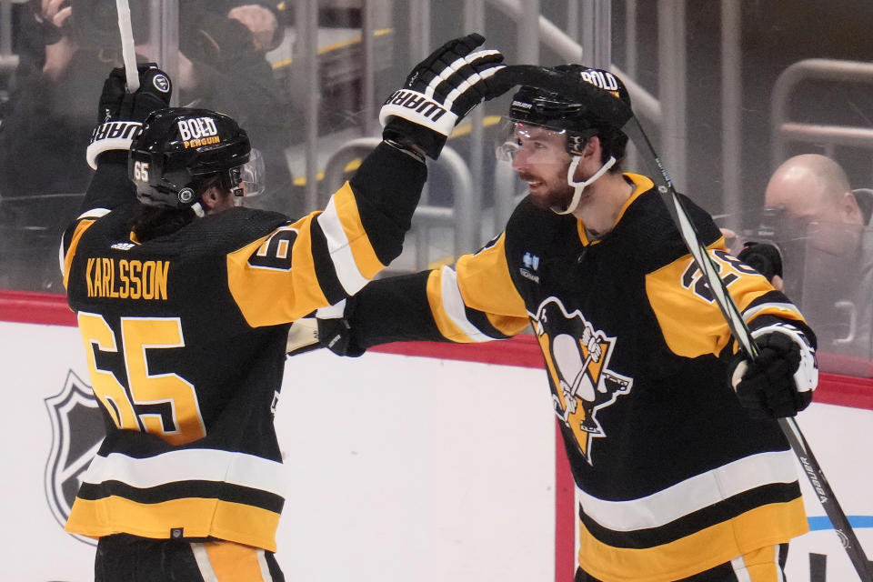 Pittsburgh Penguins' Marcus Pettersson, right, celebrates with Erik Karlsson (65) after scoring during the first period of an NHL hockey game against the New York Islanders in Pittsburgh, Tuesday, Feb. 20, 2024. Karlsson assisted on the goal for his 800th point in the NHL. (AP Photo/Gene J. Puskar)