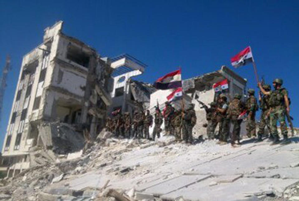 FILE - In this Wednesday, June 5, 2013 file photo released by the Syrian official news agency SANA, Syrian army troops hold up national flags in the town of Qusair, near the Lebanon border, Homs province, Syria. Two years ago, it seemed almost inevitable that President Bashar Assad would be toppled. Almost no one thinks that now. As he prepares for elections through which he is set to claim another seven-year mandate for himself, the momentum in the civil war is clearly in Assad's favor. (AP Photo/SANA, File)