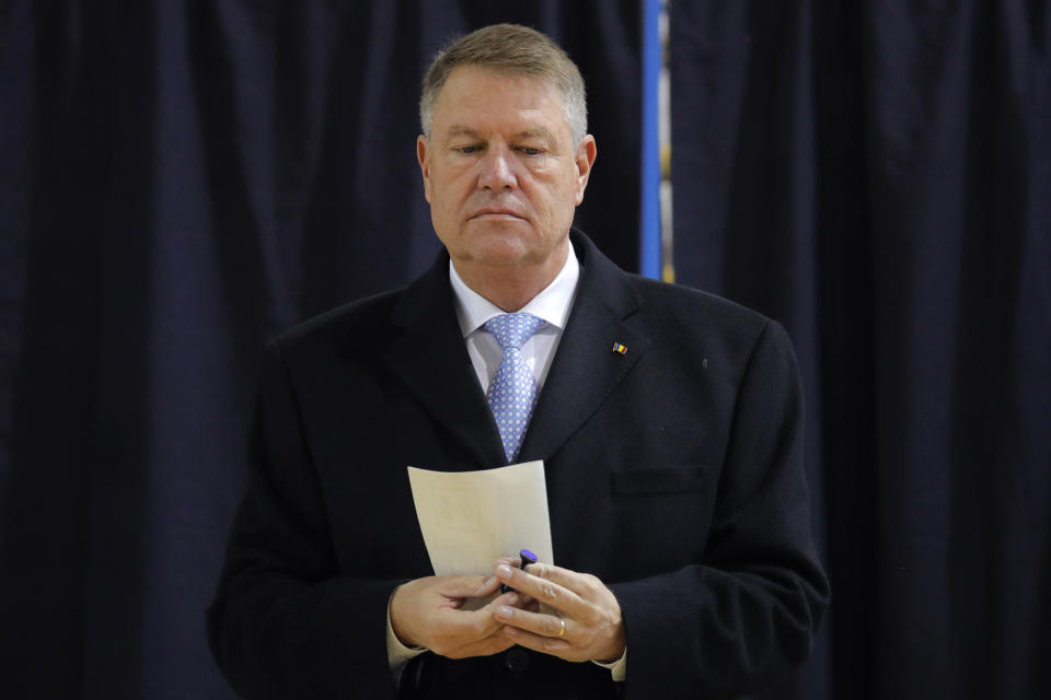 Romanian President Klaus Iohannis exits a voting cabin in Bucharest, Romania, Sunday, Nov. 24, 2019. Romanians are voting in a presidential runoff election in which incumbent Klaus Iohannis is vying for a second term, facing Social Democratic Party leader Viorica Dancila, a former prime minister, in Sunday's vote. (AP Photo/Vadim Ghirda)