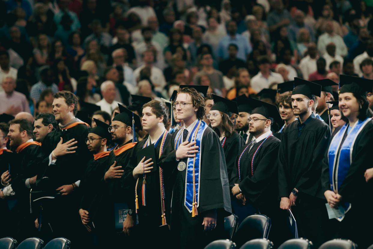 Graduates put their hands over their hearts during the national anthem during the commencement ceremony for University of Memphis graduates on Saturday, May 04, 2024, at the FedEx Forum in Downtown Memphis.