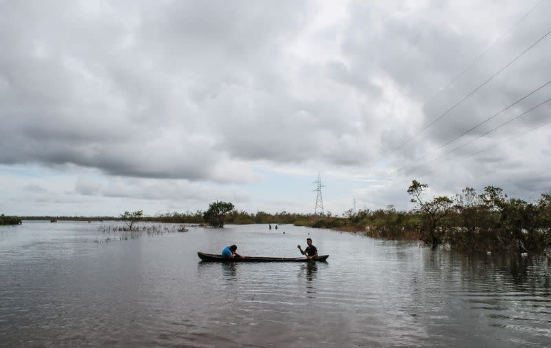 FILE PHOTO: Indigenous Miskito men use a boat to cross a road flooded by the Wawa Boom river due to heavy rain caused by Hurricane Iota as it passed through the Caribbean coast in Bilwi
