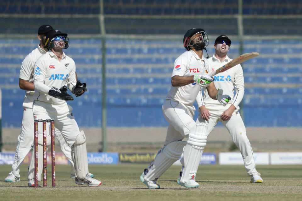 Pakistan's Shan Masood, second right, follows the ball as playing a shot as New Zealand's players watch during the fifth day of the second test cricket match between Pakistan and New Zealand, in Karachi, Pakistan, Friday, Jan. 6, 2023. (AP Photo/Fareed Khan)