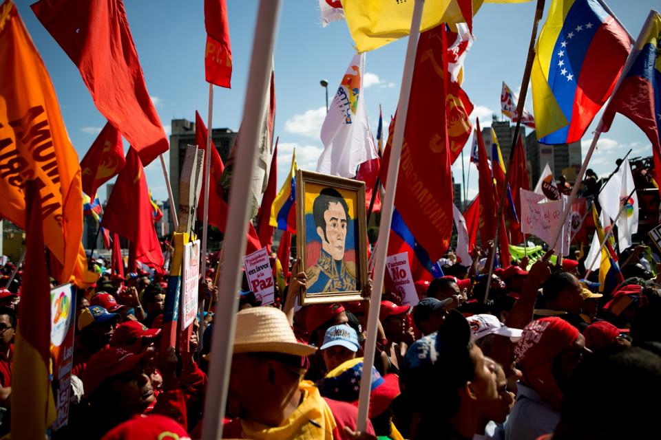 Supporters of Venezuela's President Nicolas Maduro attend a pro-government rally, one holding a painting of independence hero Simon Bolivar, along Bolivar Avenue in Caracas, Venezuela, Saturday, Feb. 15, 2014. Venezuela's President Nicolas Maduro called for the rally after days of anti-government student protests. (AP Photo/Alejandro Cegarra)