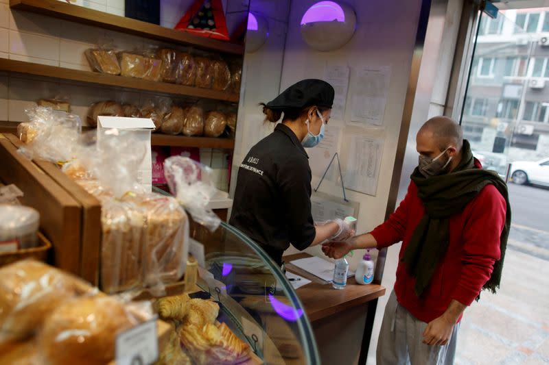 A customer has his temperature checked at a cafe of the French bakery Comptoirs de France in Beijing as the country is hit by an outbreak of the novel coronavirus