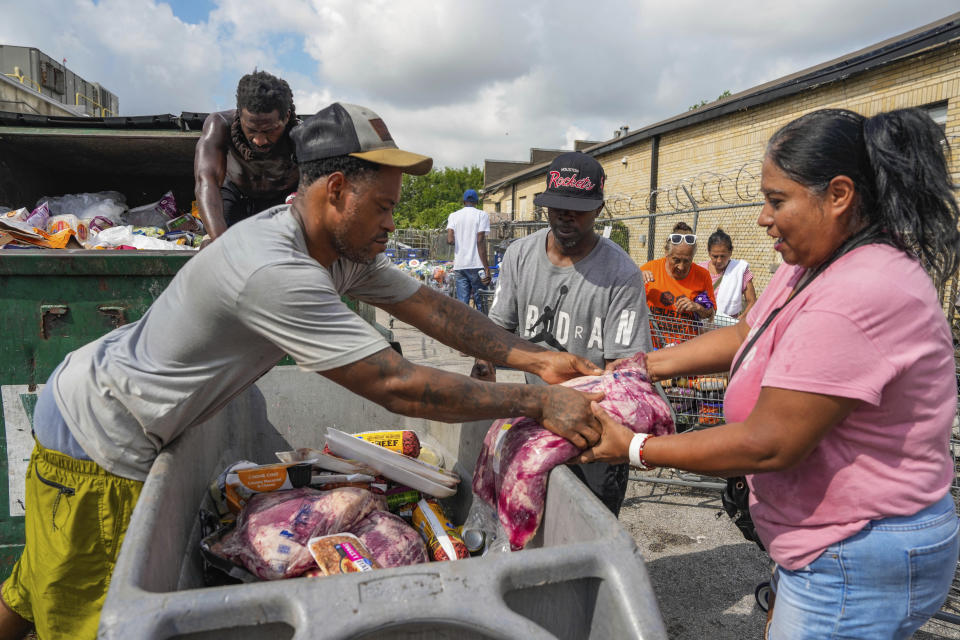East End resident Pollo hands Laura Galvan brisket found as they sifted through perishable foods that were left outside of a Kroger due to power outages from the recent Hurricane Beryl that made landfall in Houston on Tuesday, July 9, 2024. (Raquel Natalicchio/Houston Chronicle via AP)
