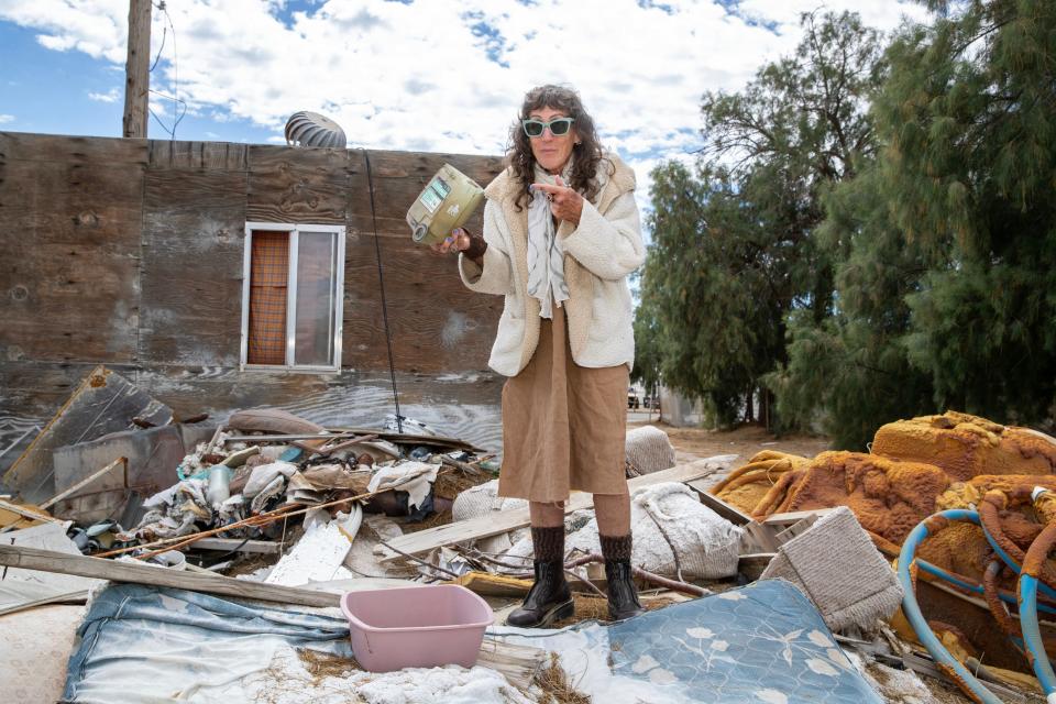 Photographer Brenda Ann Kenneally stands atop a pill of trash in an alley way in Bombay Beach, Calif., on March 19, 2024. Kenneally is putting on the second annual Bombay Beach Fashion show this coming Saturday.