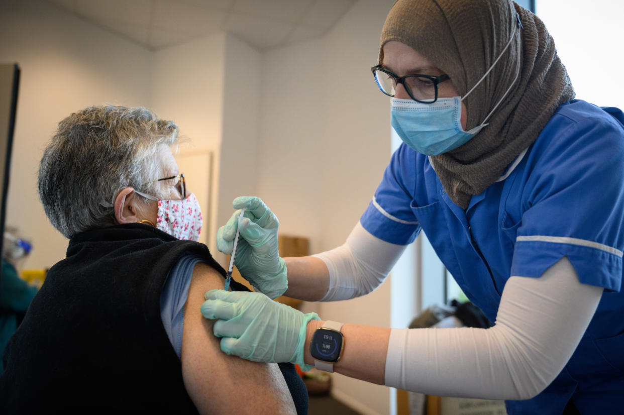 LONDON, ENGLAND - JANUARY 07: Bridget Connolly receives the first of her two jabs of the Pfizer/BioNTech COVID-19 vaccine from a member of the Newham Health Trust team at the Sir Ludwig Guttmann Building on January 07, 2021 in London, England. The UK aims to vaccinate all over-70s, front-line health workers, and the most clinically vulnerable by mid February, when its current lockdown rules will be reviewed. That would require around 13 million covid-19 vaccinations. As of Tuesday, the country had vaccinated more than 1.3 million people. (Photo by Leon Neal/Getty Images)