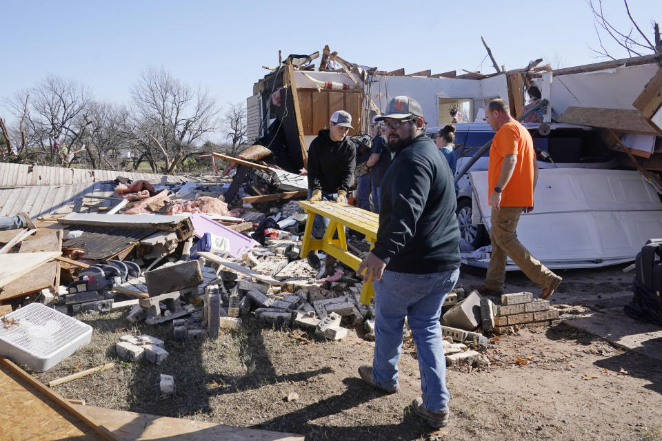 Adam Lee, left, and Jr. Ibarra, right, carry a table from a friend's home after it was destroyed by a tornado, Tuesday, Dec. 13, 2022, in Wayne, Okla. (AP Photo/Sue Ogrocki)