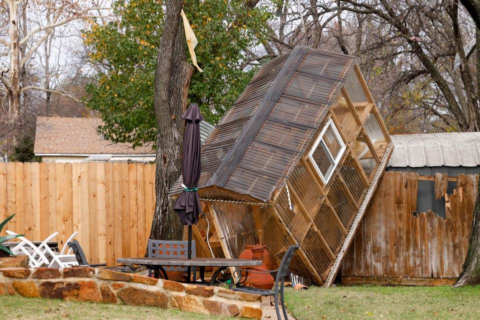 A greenhouse sits on a fence in the backyard of Randy Popiel’s home after a possible tornado in Grapevine, Texas (© 2022 Elías Valverde II / The Dallas Morning News)