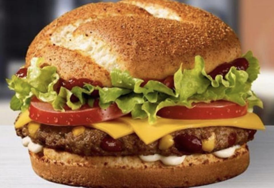 A thick brioche-type burger with relish, cheese slices, tomatoes, and lettuce