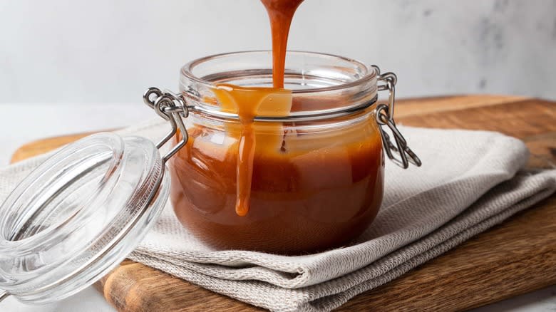 salted caramel sauce pouring into small jar with lid