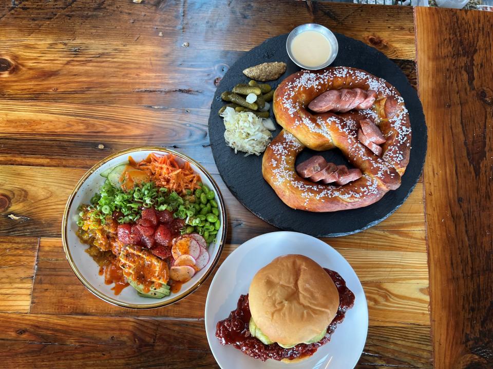 Clockwise from left: tuna poke, a pretzel with beer cheese and a buttermilk fried chicken sandwich with Korean barbecue at Big Grove Brewery in Sherman Hill on July 27, 2022. The brewery based in Solon just opened a location in Des Moines.