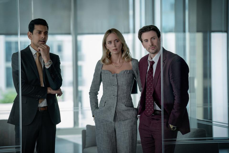 Emily Blunt (center, with Amit Shah and Chris Evans) stars as a working-class single mom who gets entrenched in a racketeering scheme in the Netflix crime drama "Pain Hustlers."