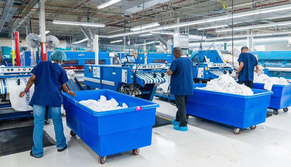 Rosalyn Burch, from left, Michael Alexander and Lawrence Parker feed linens through an automatic folder at the Goodwill's James O. Wright Center for Work & Training in Milwaukee.