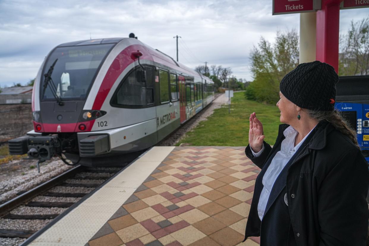 Judy Rohmann, a 25-year Austin resident from the United Kingdom, waves at a MetroRail conductor as the train approaches CapMetro's Crestview station on Friday. "It'd be nice if it went further," Rohmann said of the train. Officials this week unveiled five new options for an Austin light rail system.