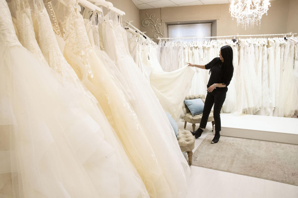 FILE - Anita Galafate checks wedding dresses in a shop in Rome, Tuesday, March 9, 2021. Couples in the U.S. are racing to the altar amid a vaccination-era wedding boom that has venues and other vendors in high demand. (AP Photo/Alessandra Tarantino, File)
