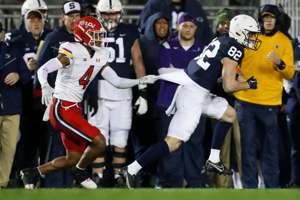 Nov 12, 2022; University Park, Pennsylvania, USA; Penn State Nittany Lions wide receiver Liam Clifford (82) runs with the ball as Maryland Terrapins defensive back Tarheeb Still (4) pulls on the back of his jersey during the fourth quarter at Beaver Stadium. Penn State defeated Maryland 30-0.