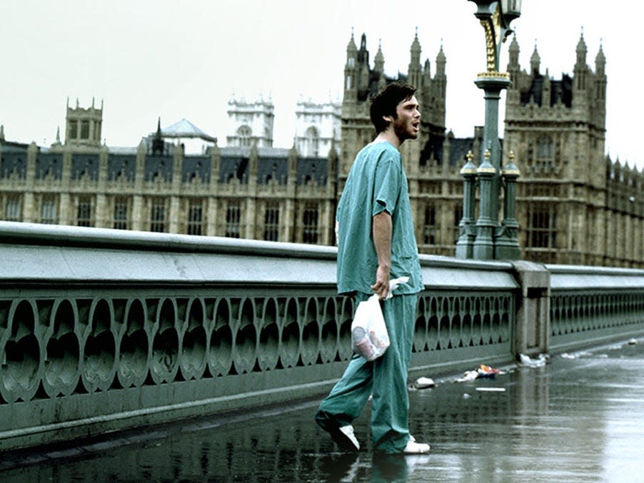 Cillian Murphy in a scene from "28 Days Later" where Jim is walking across London Bridge wile wearing a hospital gown and carrying a plastic bag.