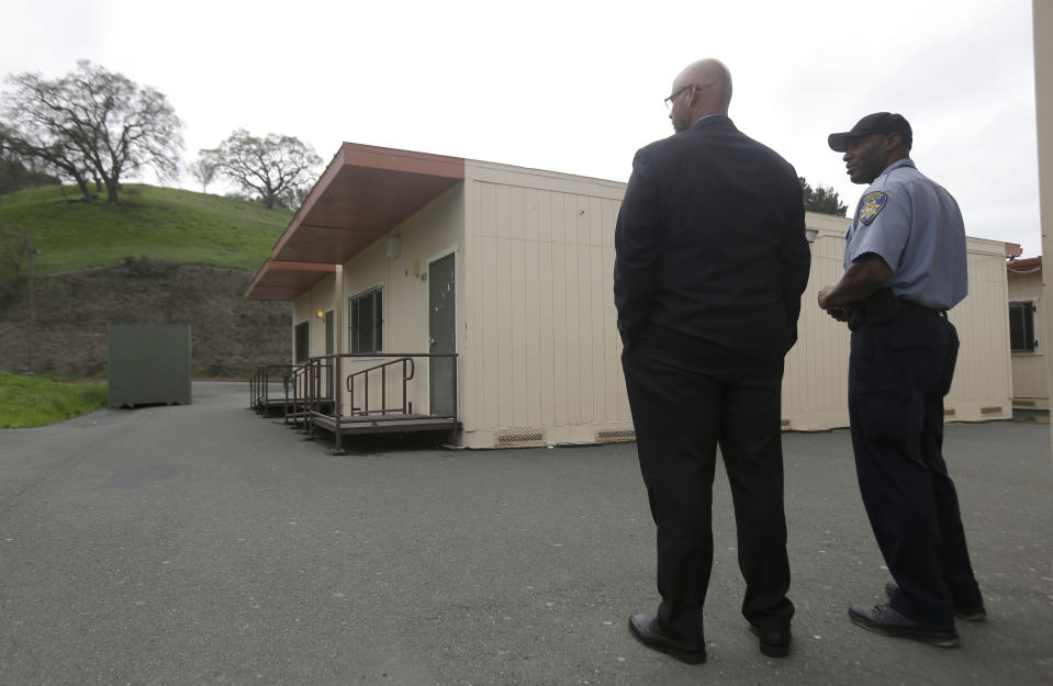 Adam Taylor, executive director of kindergarten through 12th grade school operations for West Contra Costa Unified School District, left, stands next to a security officer in front of the health clinic at the Hercules Middle-High School campus in Hercules, Calif., Tuesday, March 4, 2014. Police on Tuesday were investigating reports of a brutal assault of a transgender teen who was using a high school bathroom in a San Francisco Bay Area suburb. The 15-year-old student told officers he was leaving a boy's bathroom at Hercules High School on Monday when three teenage boys pushed him inside a handicapped stall and physically and sexually assaulted him, Hercules police Detective Connie Van Putten said. (AP Photo/Jeff Chiu)