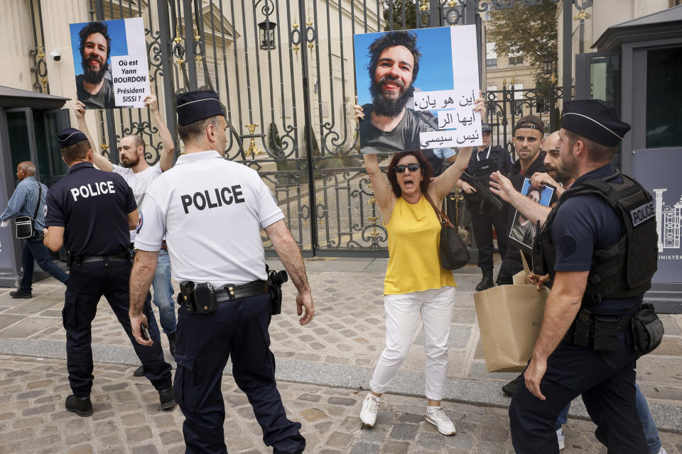 Police officers escort Isabel Leclercq, right, the mother of missing traveler Yann Bourdon in Egypt as she holds a picture of her son during during a march with relatives and friends near the Elysee Palace during Egyptian President Abdel Fattah el-Sissi visiting French President Emmanuel Macron in Paris, Friday, July 22. The family of a French backpacker who went missing in Egypt have used a visit to Paris by the Egyptian president to press for an investigation into his disappearance. Placards reads, where is Yann Bourdon, President Sissi. (AP Photo/Thomas Padilla)