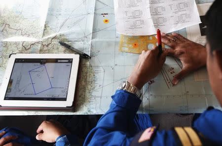 A Malaysian Maritime Enforcement Agency pilot studies the map onboard a Japan Coast Guard Gulfstream V Jet aircraft, customized for search and rescue operations, as they search for the missing Malaysia Airlines MH370 plane over the waters of the South China Sea in this file photo taken March 15, 2014. REUTERS/Edgar Su