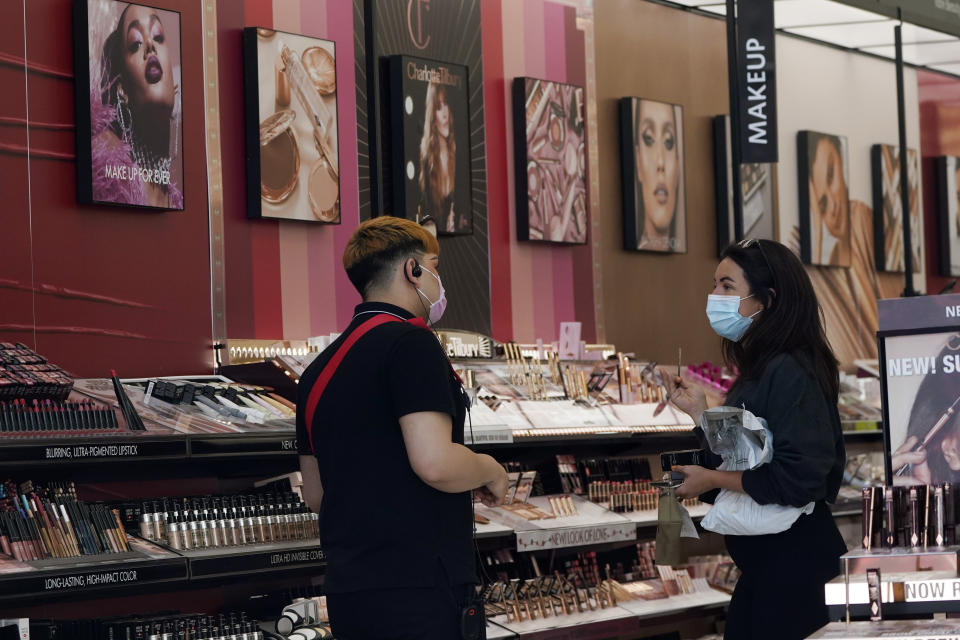 A worker, at left, tends to a customer at a cosmetics shop amid the COVID-19 pandemic Thursday, May 20, 2021, in Los Angeles. (AP Photo/Marcio Jose Sanchez)