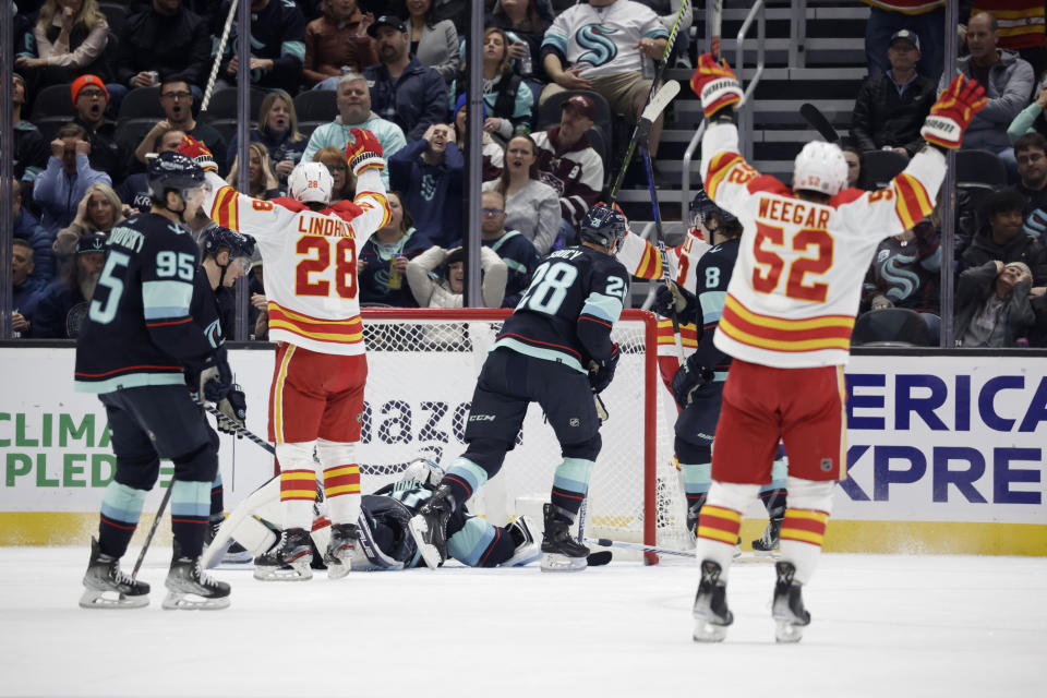 Calgary Flames defenseman MacKenzie Weegar (52) and center Elias Lindholm (28) celebrate a goal by right wing Tyler Toffoli against the Seattle Kraken during the first period of an NHL hockey game, Friday, Jan. 27, 2023, in Seattle. (AP Photo/John Froschauer)