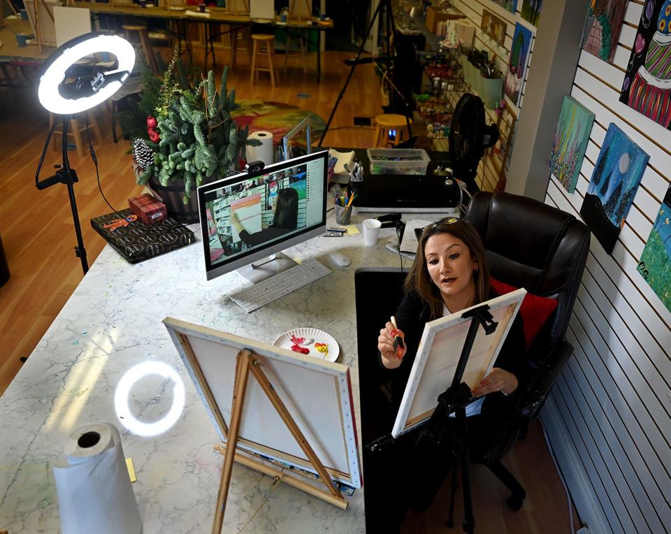 A ring light illuminates Mahsa Ghavamian, owner of Canvas n Cup in Westborough, as she teaches an online acrylic painting class to a group of corporate customers, Nov. 19, 2021. Before the pandemic, her classes were all conducted in person.