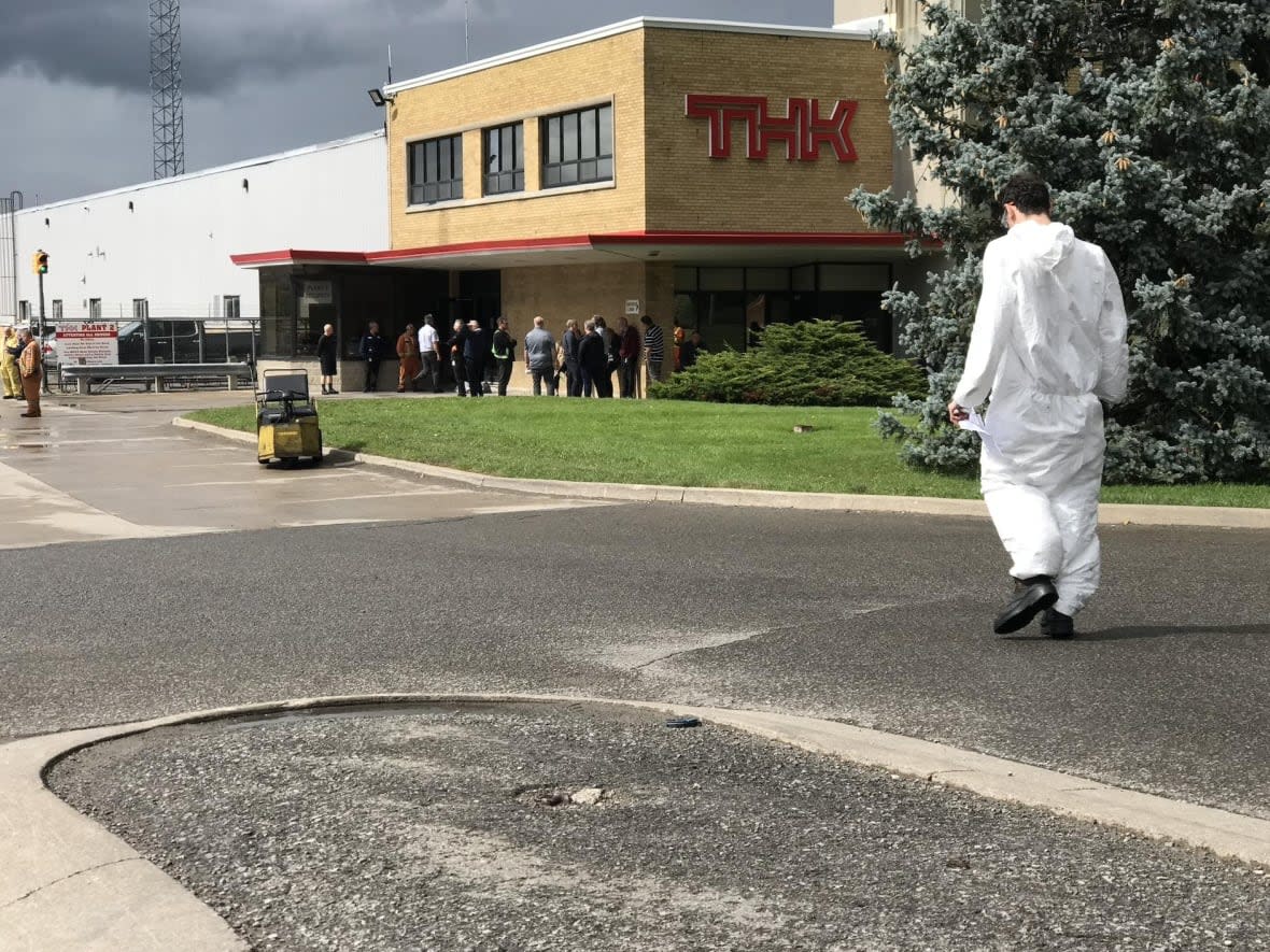 People gather outside THK Rhythm Automotive Canada Ltd. on Louth Street in St. Catharines, Ont., on Tuesday after a hydrochloric acid spill in the morning sent workers to hospital. (James Dunne/CBC - image credit)