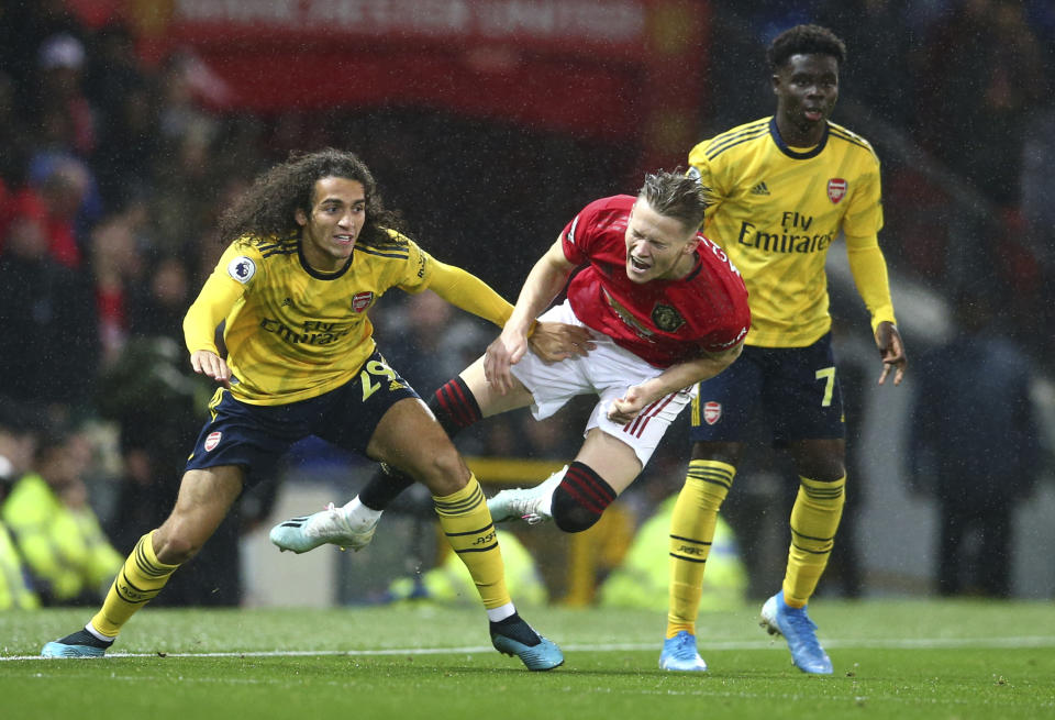 Manchester United's Scott McTominay, centre, vies for the ball with Arsenal's Matteo Guendouzi, left, during the English Premier League soccer match between Manchester United and Arsenal at Old Trafford in Manchester, England, Monday, Sept. 30, 2019. (AP Photo/Dave Thompson)