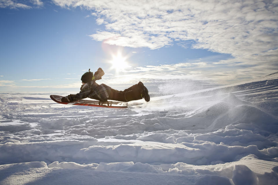 Boy hitting a jump with his toboggan