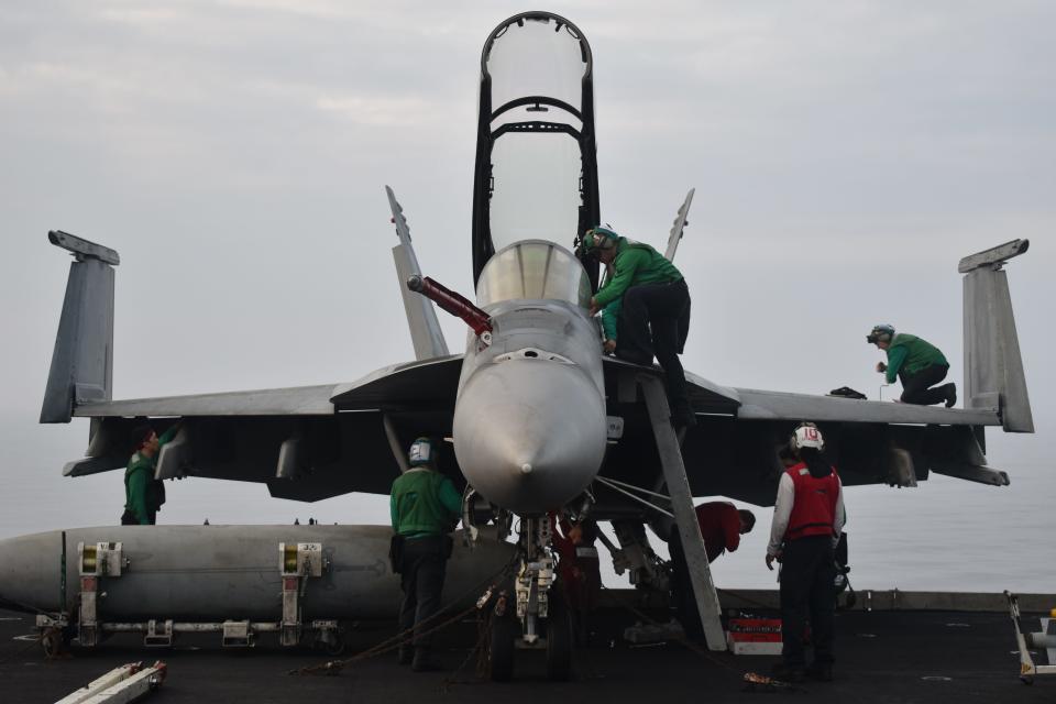 Sailors perform work to a fighter jet on the USS Dwight D. Eisenhower.