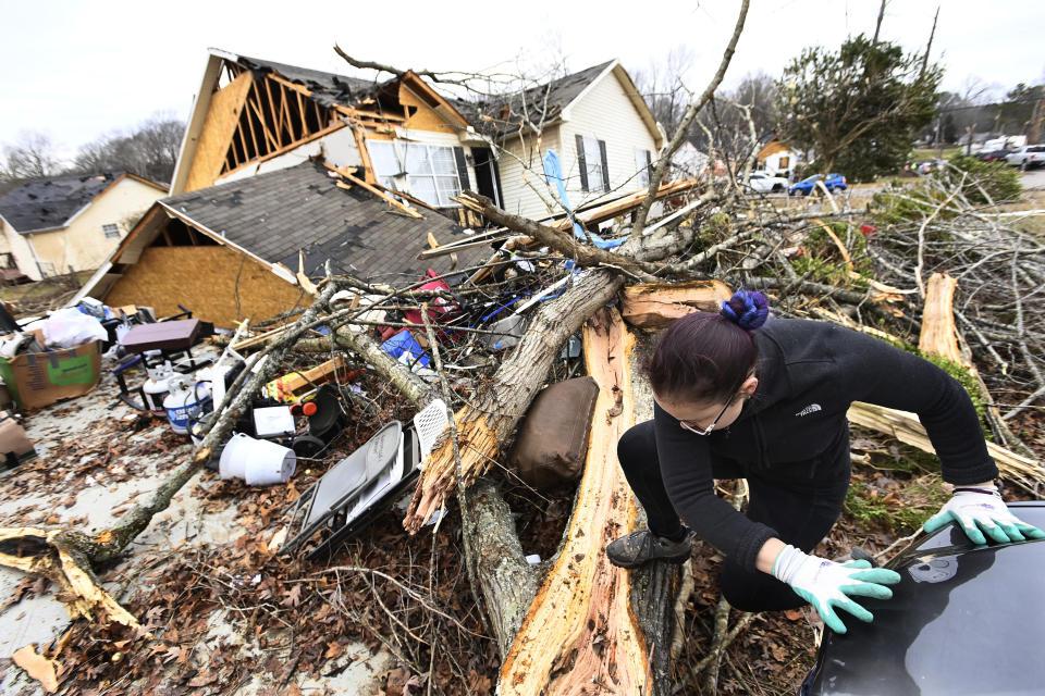 A resident climbs over debris after her friend's home was lifted off its foundation on Sunday, Dec. 10, 2023, Clarksville, Tenn. Tornados caused catastrophic damage in Middle Tennessee Saturday afternoon and evening. (AP Photo/Mark Zaleski)