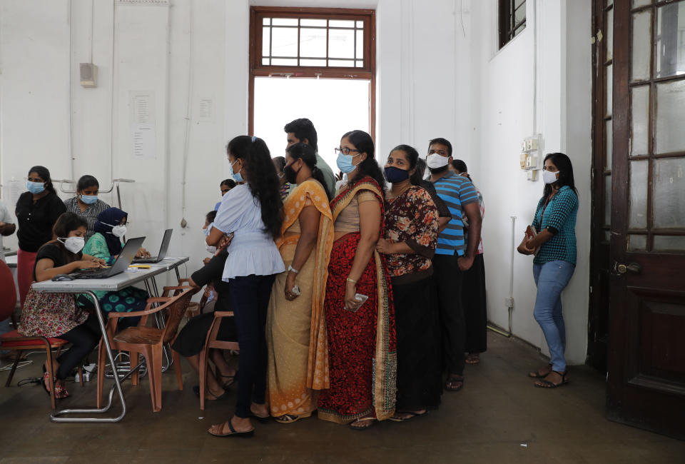 Employees of Colombo municipal council wait to give their swab samples to test for COVID-19 in Colombo, Sri Lanka, Wednesday, Oct. 7, 2020. Authorities in Sri Lanka on Wednesday widened a curfew and warned of legal action against those evading treatment for COVID-19 after reporting an escalating cluster centered around a garment factory in the capital's suburbs. (AP Photo/Eranga Jayawardena)