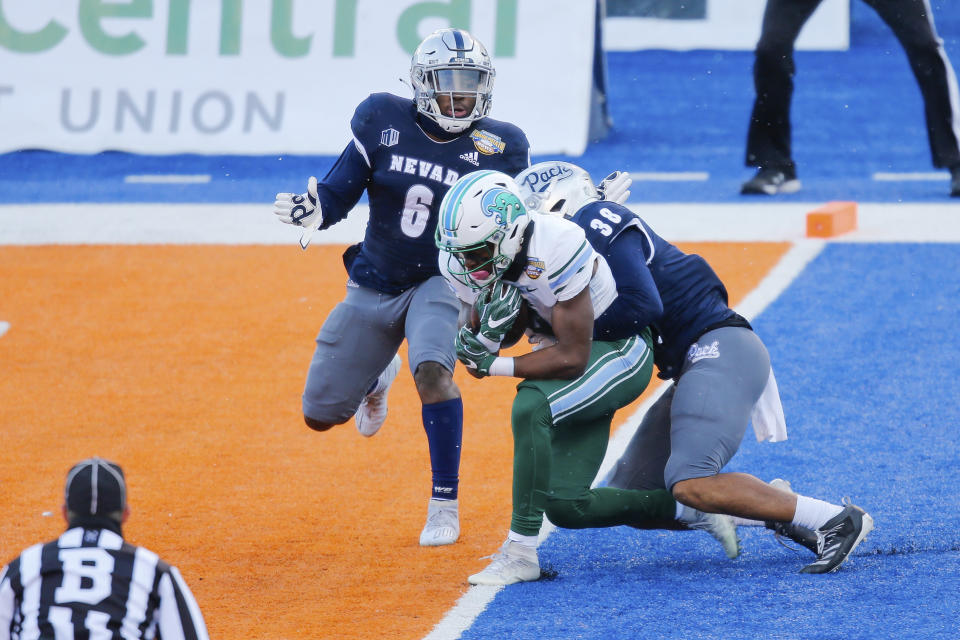 Tulane wide receiver Jha'Quan Jackson (4) drags Nevada defensive back Christian Swint (38) into the end zone for a touchdown during the first half of the Idaho Potato Bowl NCAA college football game, Tuesday, Dec. 22, 2020, in Boise, Idaho. (AP Photo/Steve Conner)