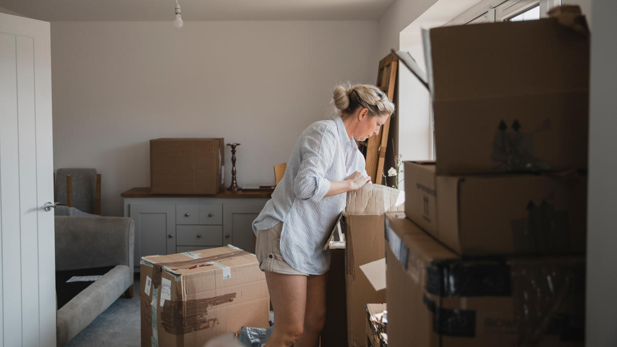 Mature woman is unpacking boxes in her new home.