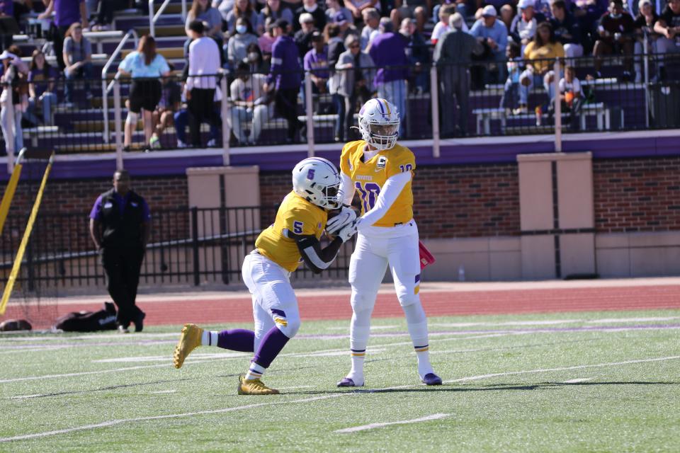 Kansas Wesleyan's Isaiah Randalle (10) hands the ball off to CJ Fluker (5) during Saturday's game against McPherson at Graves Family Sports Complex.