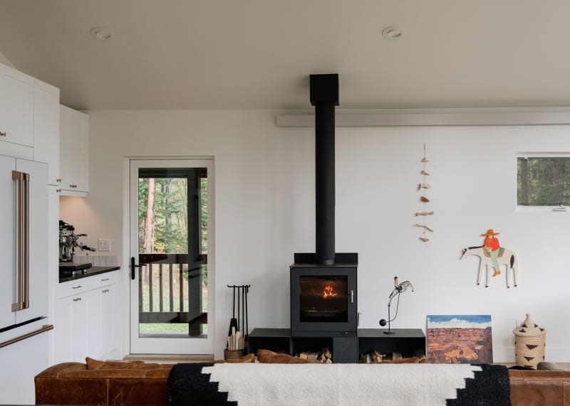 Wood stove lit in light filled living room.