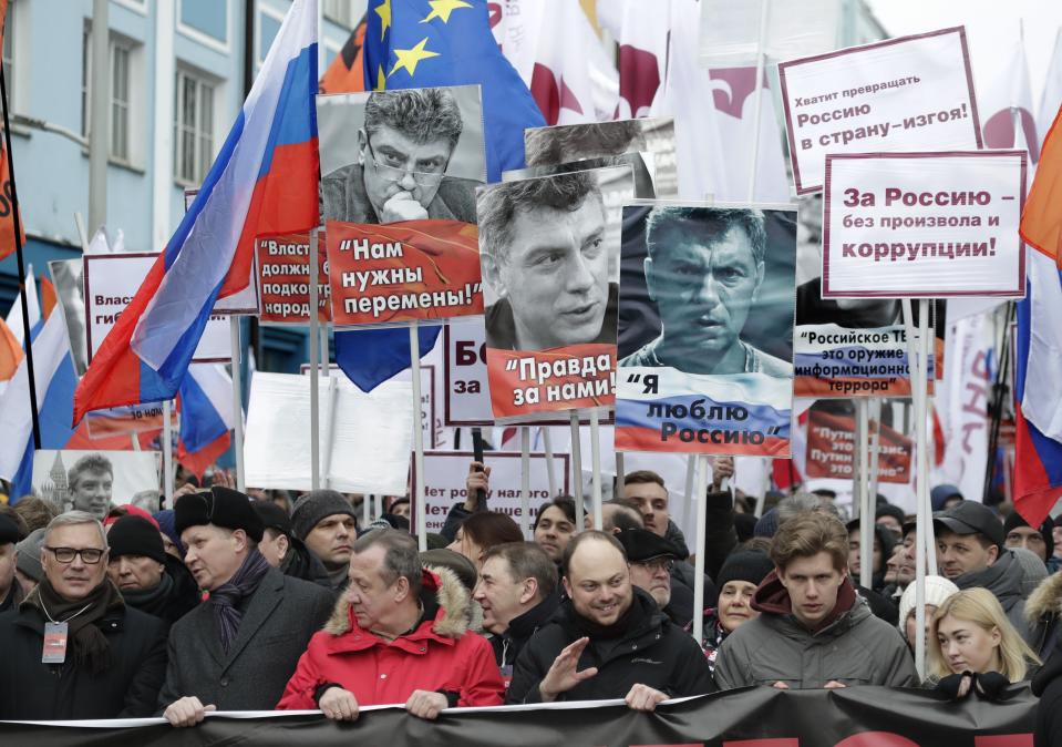 Demonstrators, with flags of different opposition movements and portraits of Boris Nemtsov, march in memory of opposition leader Boris Nemtsov in Moscow, Russia, Sunday, Feb. 24, 2019. Thousands of Russians took to the streets of downtown Moscow to mark four years since Nemtsov was gunned down outside the Kremlin. Former Russian Prime Minister, and one of opposition leaders, Mikhail Kasyanov is on the left. (AP Photo/Pavel Golovkin)