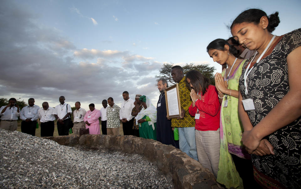 In this photo taken Thursday, Sept. 20, 2012, Preetika Bhanderi of the Hindu Council of Africa, 2nd right, leads a prayer by religious leaders of different faiths around a pile of charred elephant ivory at a site in Nairobi National Park where Kenyan officials burned hundreds of ivory tusks in 1989 to draw attention to the slaughter of elephants, in Nairobi, Kenya. Seeing a dire situation grow worse, the animal conservation group the World Wildlife Fund (WWF) enlisted religious leaders on Thursday, Sept. 20, 2012 in the fight to end the slaughter of Africa's elephants and rhinos by poachers, hoping that religion can help save some of the world's most majestic animals. (AP Photo/Ben Curtis)