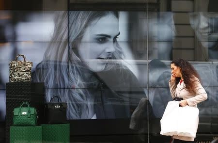 A woman walks past a video display in the shop window of a Mulberry store in central London October 14, 2014. REUTERS/Andrew Winning/Files